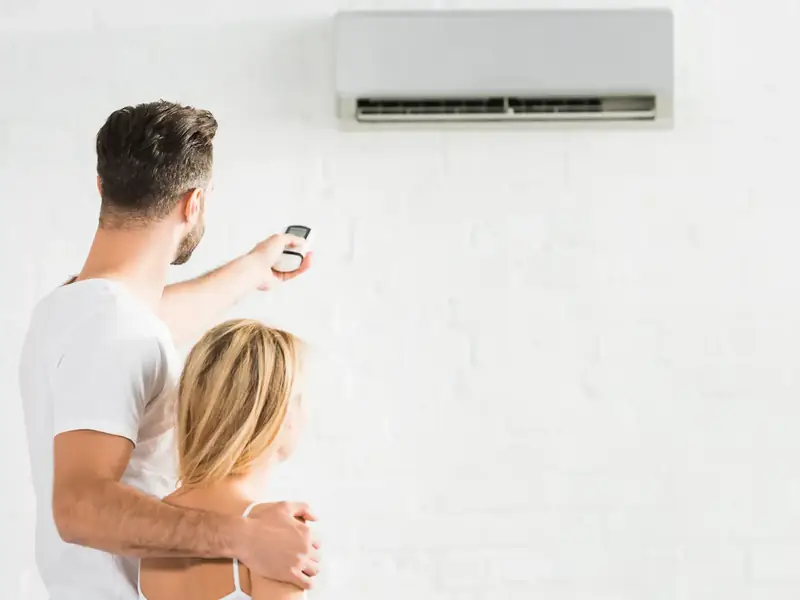 Couple profitant de la fraîcheur d'une pièce climatisée réglée avec modération