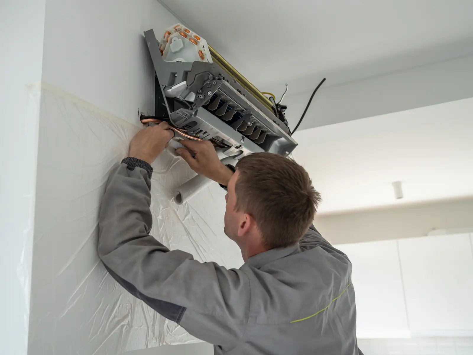Installateur fixant un split mural lors de la pose d'une climatisation