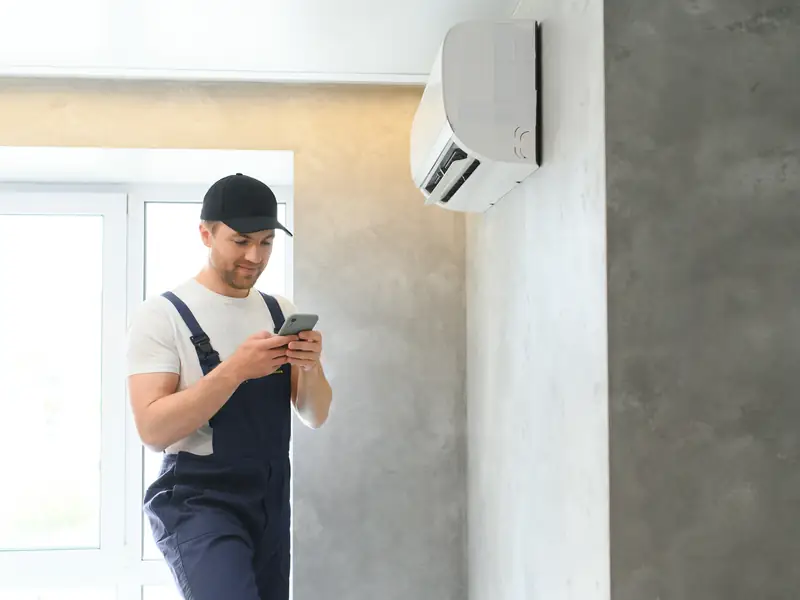 Installateur vérifiant une unité intérieure de climatisation tout juste posée