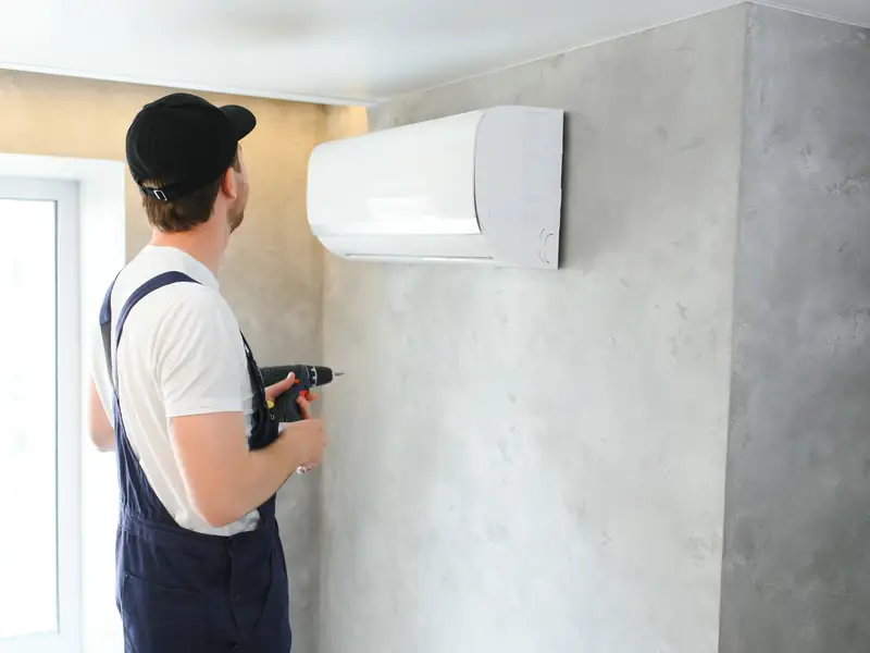 Technicien fixant une unité intérieure de climatisation murale
