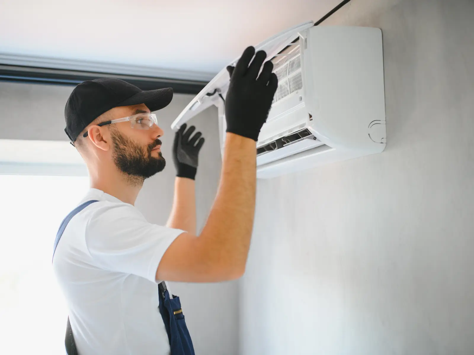 Technicien intervenant sur un climatiseur mural qui rejette de l'air chaud