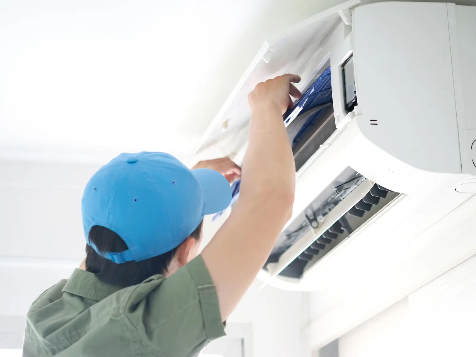 Technicien ouvrant une unité intérieure de climatisation pour la contrôler