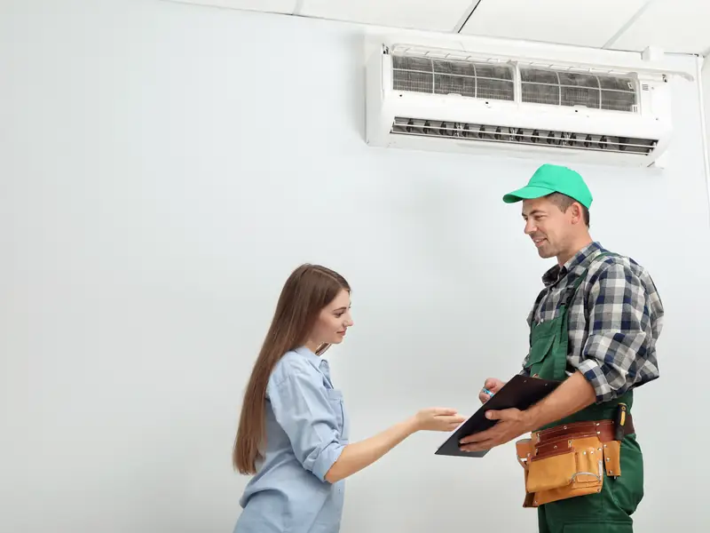 Technicien remettant à une cliente le compte rendu d'entretien de sa climatisation