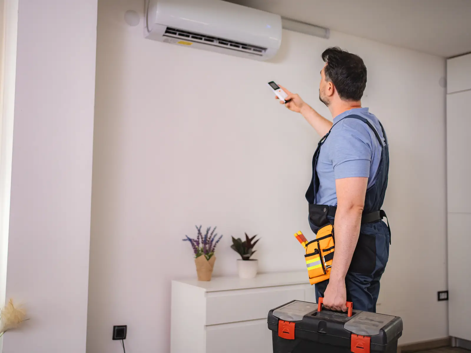Technicien testant une climatisation murale avec sa télécommande après réparation