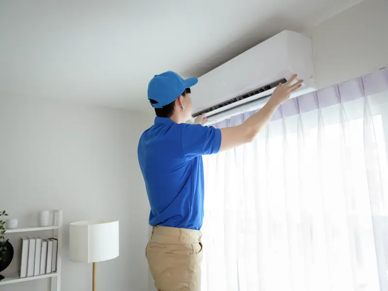 Technicien vérifiant une unité murale avant l'arrivée des vacanciers