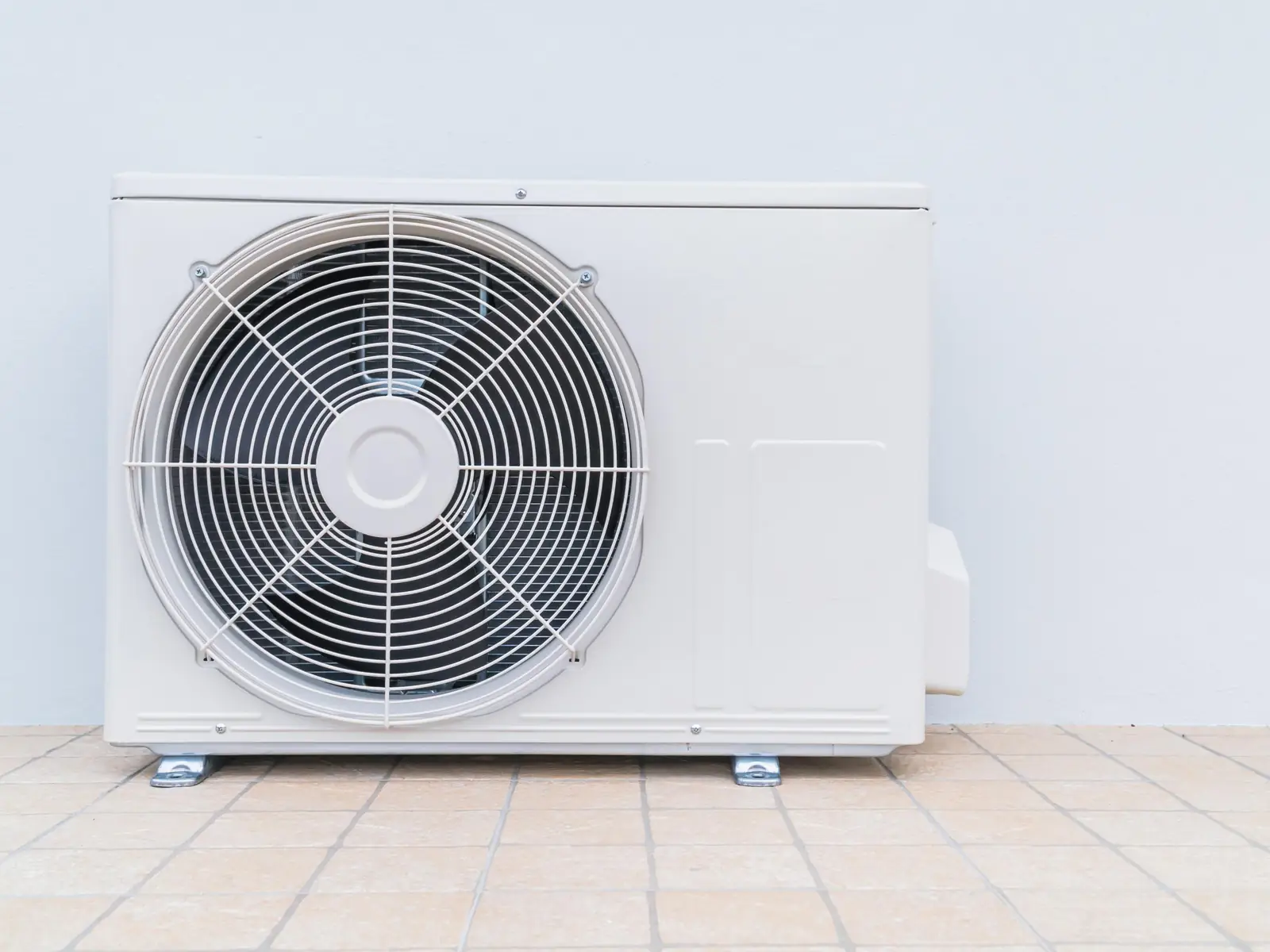 Unité extérieure de climatisation posée au sol à côté d'un logement