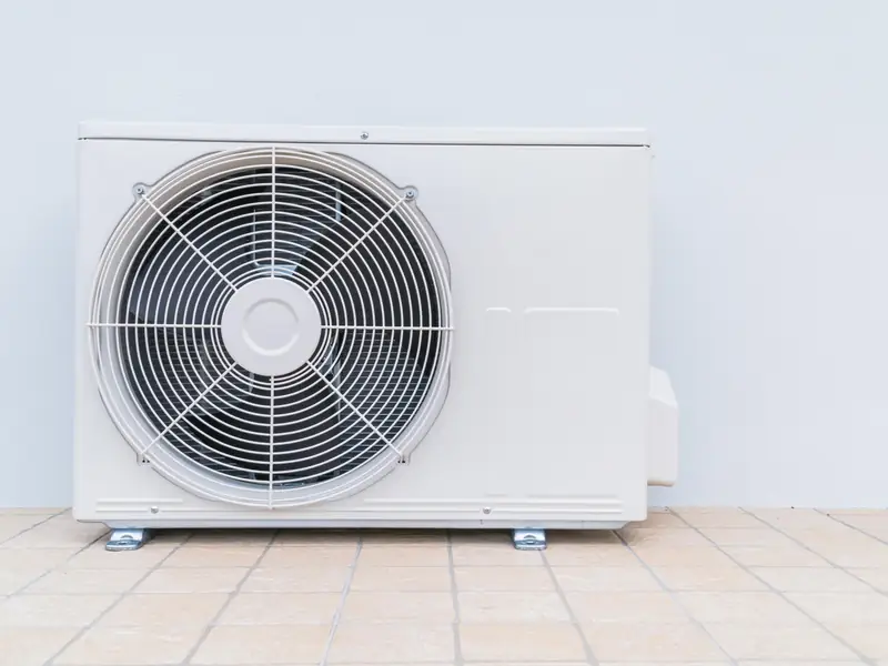 Unité extérieure de climatisation posée au sol près d'une maison
